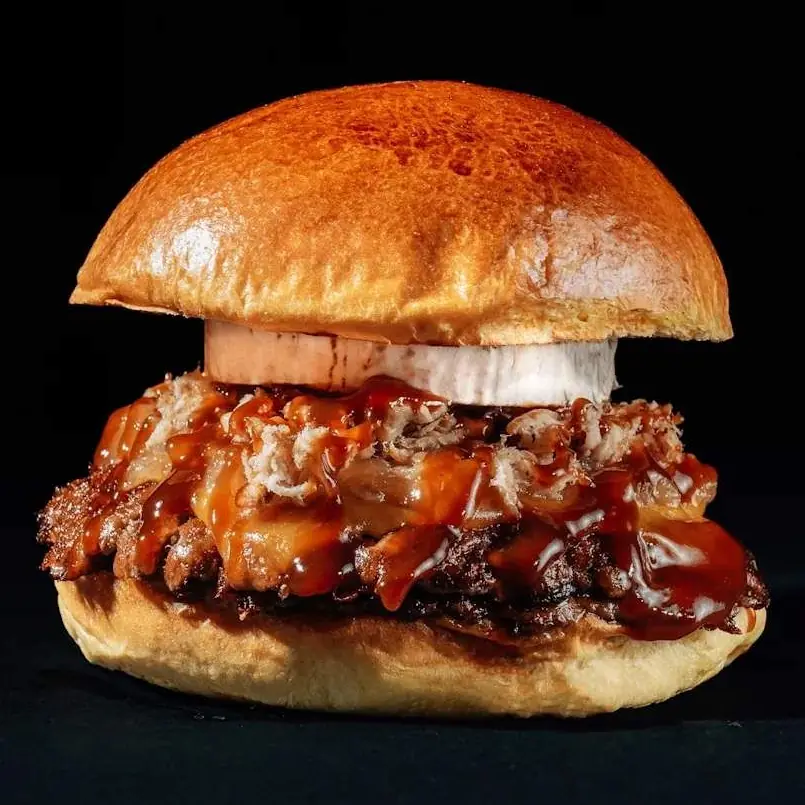 BBQ Extreme Burger: doble carne smash con cheddar ahumado, rulo de cabra, cebolla caramelizada, pulled pork y salsa BBQ